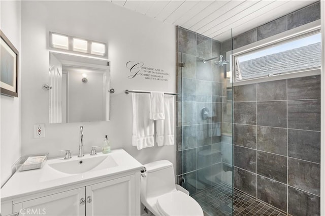 bathroom featuring vanity, a tile shower, and toilet