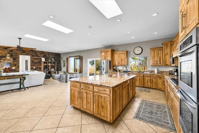 7423 Juniper Rd, Joshua Tree, CA 92252 - kitchen with an island with sink, stainless steel appliances, open floor plan, light tile patterned floors, and a skylight