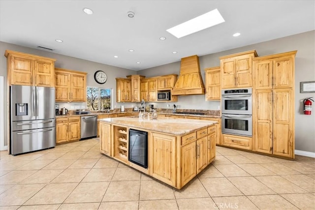 7423 Juniper Rd, Joshua Tree, CA 92252 - kitchen featuring beverage cooler, premium range hood, stainless steel appliances, light tile patterned floors, and a skylight