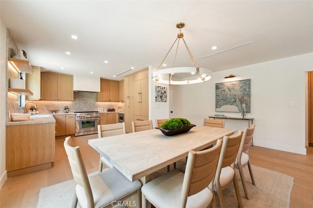 dining room with recessed lighting, baseboards, an inviting chandelier, and light wood finished floors