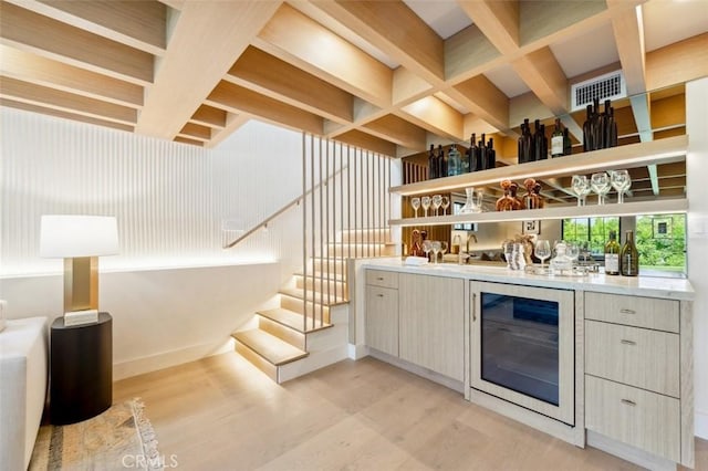 bar featuring visible vents, stairs, beverage cooler, light wood-style floors, and indoor bar