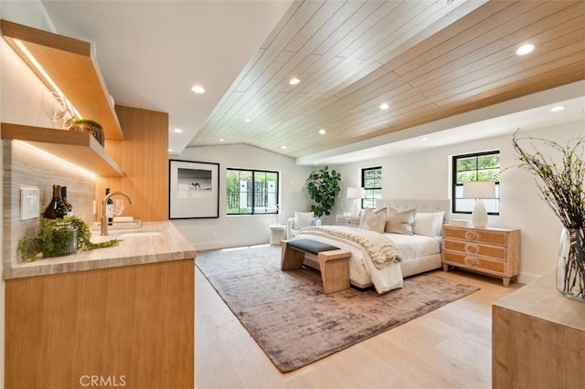 bedroom with recessed lighting, vaulted ceiling, a sink, and light wood-style floors