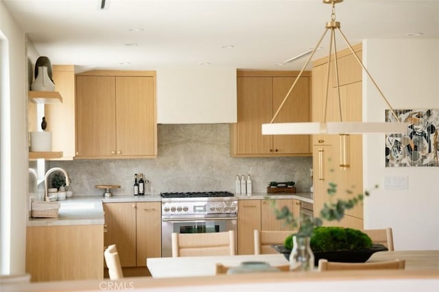 kitchen with decorative backsplash, high end stainless steel range oven, light brown cabinetry, light countertops, and a sink