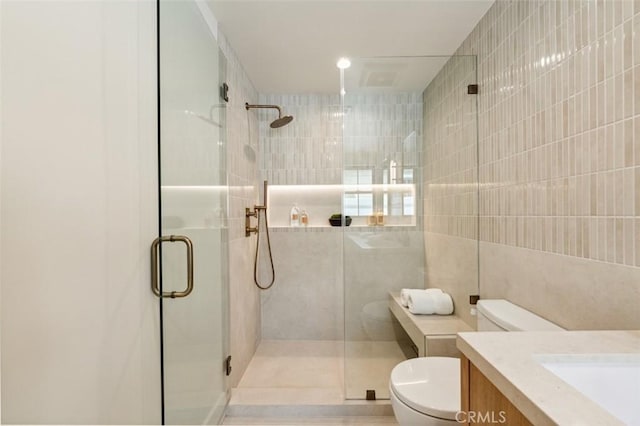 full bathroom featuring vanity, a stall shower, toilet, and tile walls