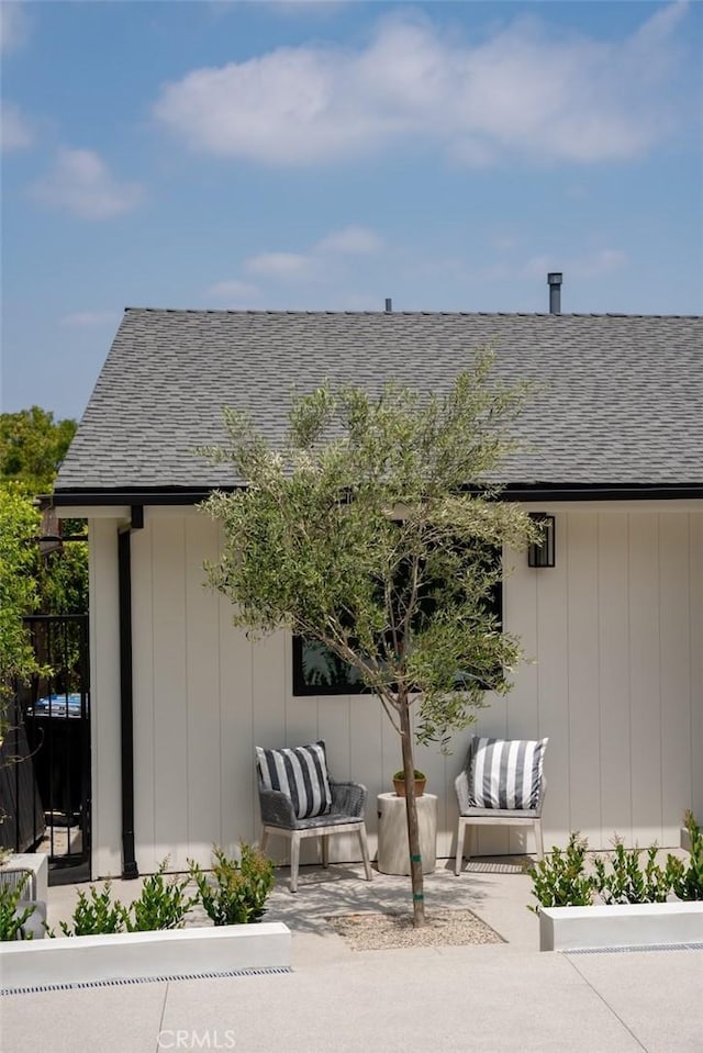 exterior space with a shingled roof and a patio area