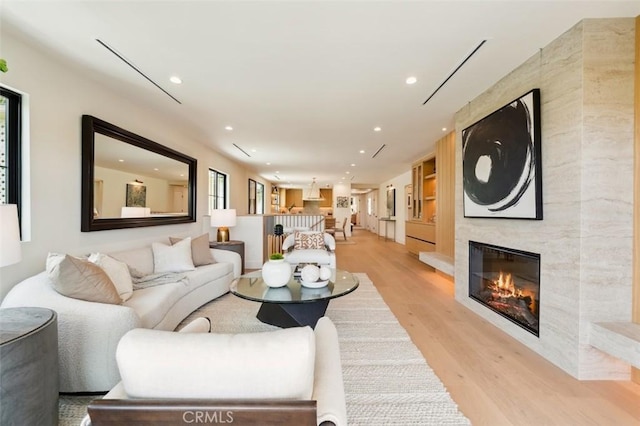 living area featuring recessed lighting, a tile fireplace, a healthy amount of sunlight, and light wood-style floors