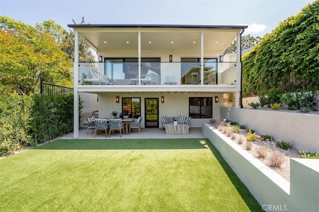 back of house featuring an outdoor living space, a yard, a balcony, and fence