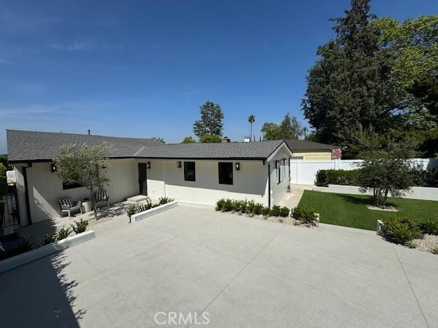 ranch-style house with a patio, fence, and a front lawn
