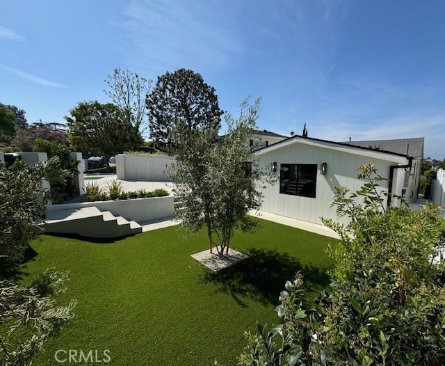 rear view of property featuring a lawn and fence