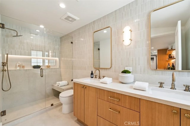 full bathroom featuring a sink, a stall shower, toilet, and tile walls