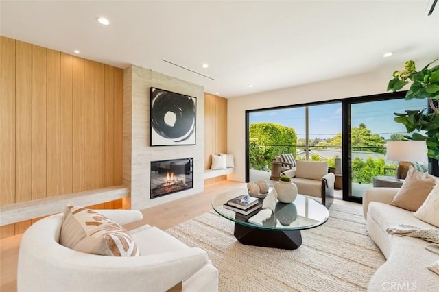 living area with recessed lighting, wood walls, wood finished floors, and a large fireplace