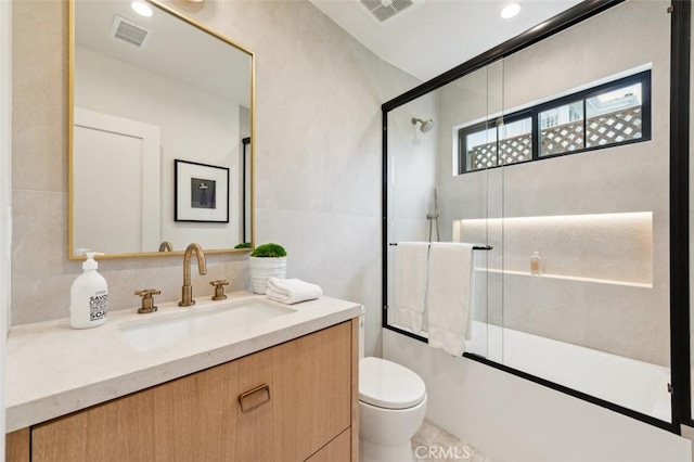 full bathroom featuring toilet, visible vents, a shower with shower door, and vanity