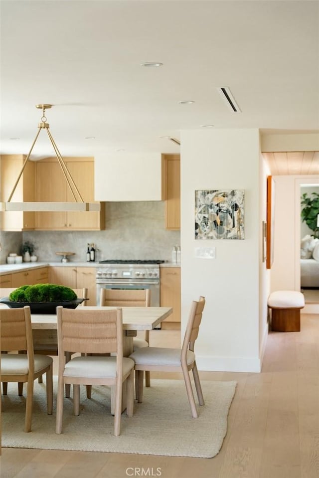 dining area featuring visible vents, light wood-style flooring, and baseboards