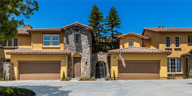 view of front of house featuring stone siding, stucco siding, a chimney, driveway, and a tile roof