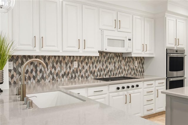 kitchen featuring a sink, white cabinets, white microwave, and double oven