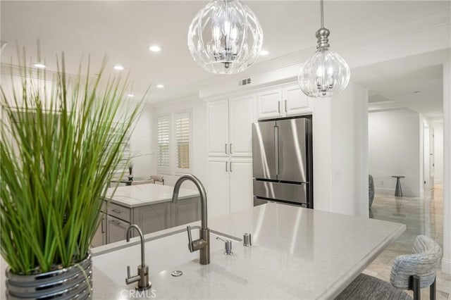 kitchen featuring visible vents, crown molding, freestanding refrigerator, a notable chandelier, and white cabinetry