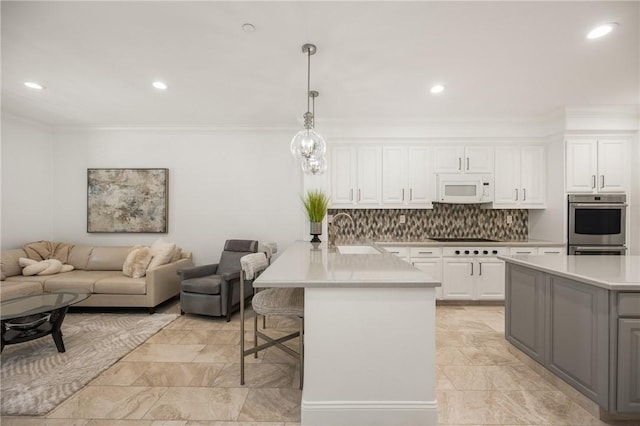 kitchen with a sink, light countertops, a breakfast bar area, open floor plan, and white microwave