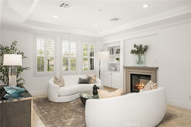 living room featuring crown molding, a glass covered fireplace, built in shelves, baseboards, and visible vents
