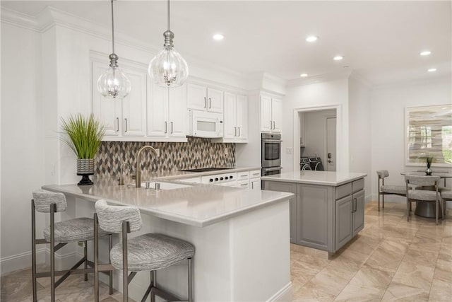 kitchen with decorative backsplash, white microwave, light countertops, white cabinetry, and a sink