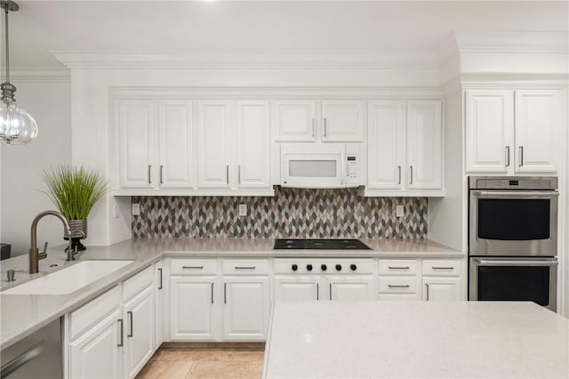 kitchen with a sink, appliances with stainless steel finishes, backsplash, and decorative light fixtures