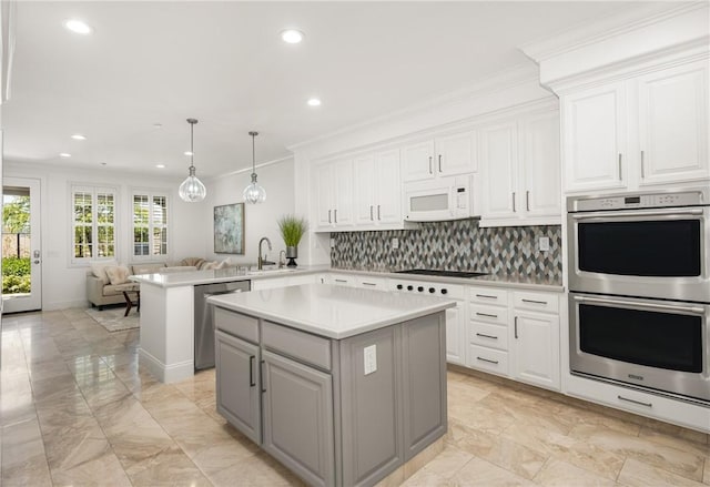 kitchen featuring decorative backsplash, a kitchen island, open floor plan, a sink, and appliances with stainless steel finishes