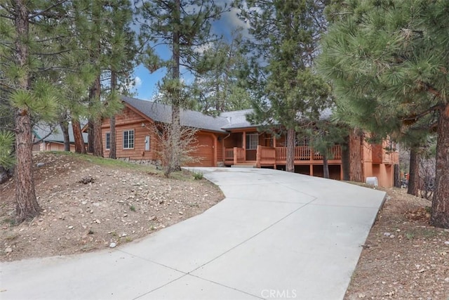 cabin with an attached garage, covered porch, and concrete driveway