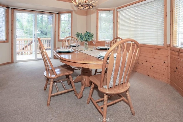 carpeted dining space featuring a healthy amount of sunlight and a notable chandelier