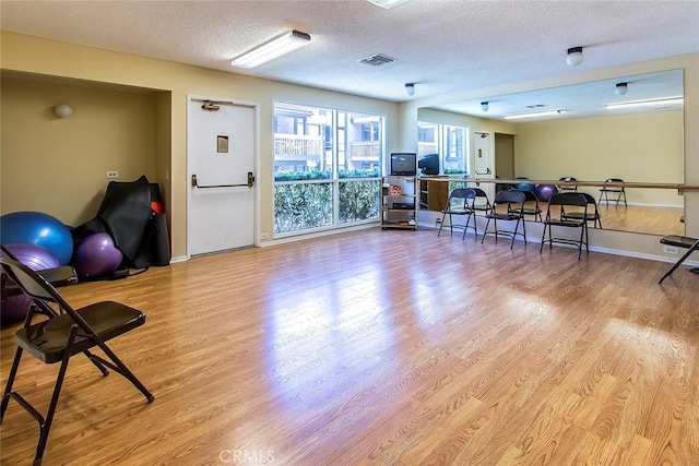 interior space featuring baseboards, light wood finished floors, a textured ceiling, and visible vents