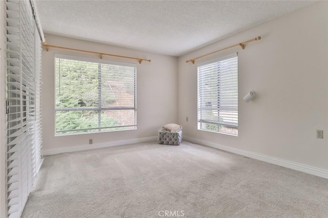 carpeted spare room featuring baseboards and a textured ceiling