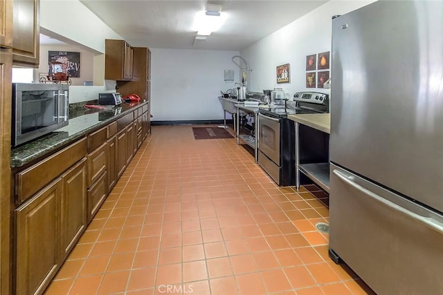 kitchen with brown cabinetry, dark countertops, and stainless steel appliances