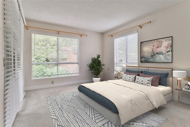 carpeted bedroom featuring baseboards, a textured ceiling, and multiple windows