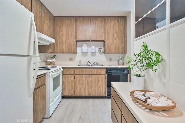 kitchen featuring a sink, white appliances, light countertops, light wood-style flooring, and under cabinet range hood