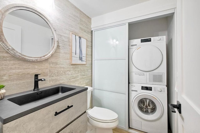 bathroom featuring stacked washer and dryer, a sink, and toilet
