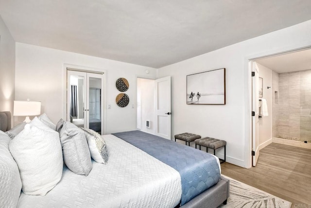 bedroom featuring french doors, connected bathroom, baseboards, and wood finished floors