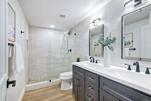 full bath featuring toilet, visible vents, a sink, and a stall shower