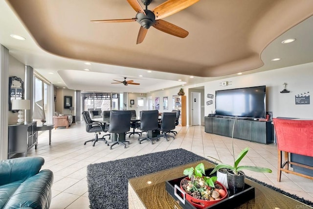 living room with light tile patterned floors, a ceiling fan, recessed lighting, and a tray ceiling