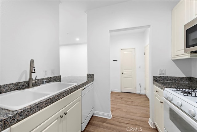 kitchen featuring a sink, white appliances, light wood finished floors, and white cabinetry
