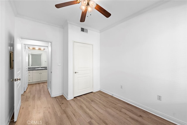 unfurnished bedroom featuring light wood-style flooring, crown molding, a sink, baseboards, and ceiling fan