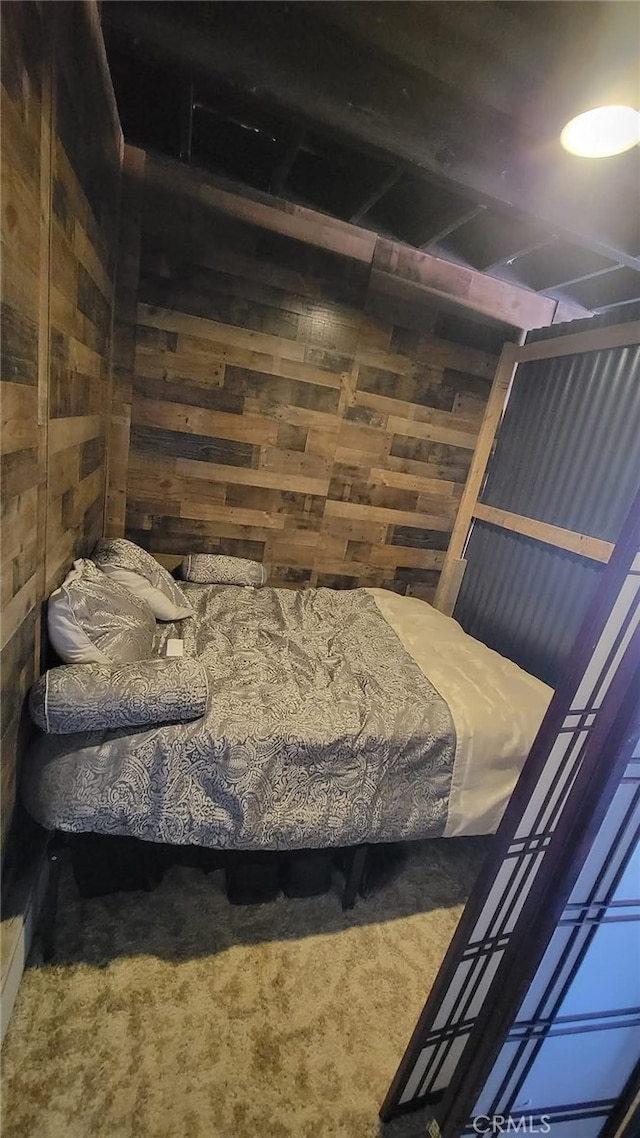 bedroom featuring carpet flooring and wood walls