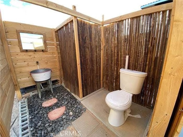 bathroom with wooden walls and toilet