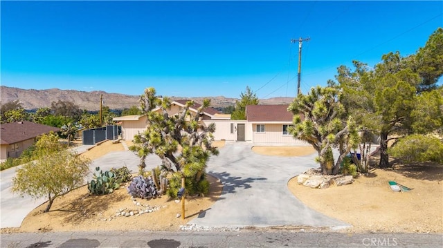view of property hidden behind natural elements with curved driveway and a mountain view