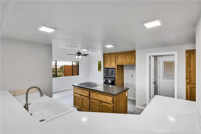 kitchen with a sink, baseboards, light tile patterned floors, and black appliances