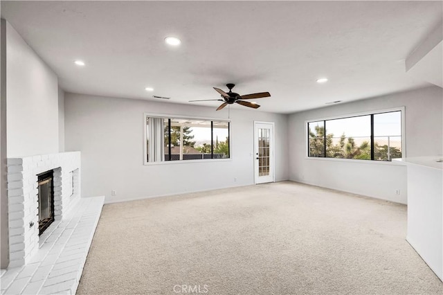 unfurnished living room with recessed lighting, light carpet, a wealth of natural light, and a fireplace