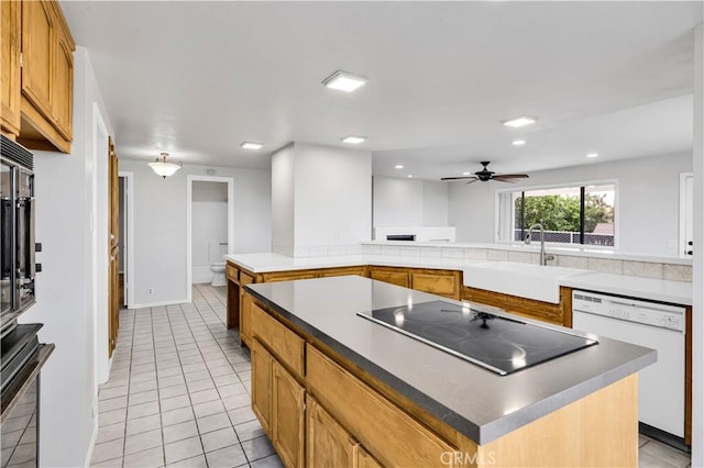 kitchen with a sink, light tile patterned floors, black electric stovetop, and dishwasher