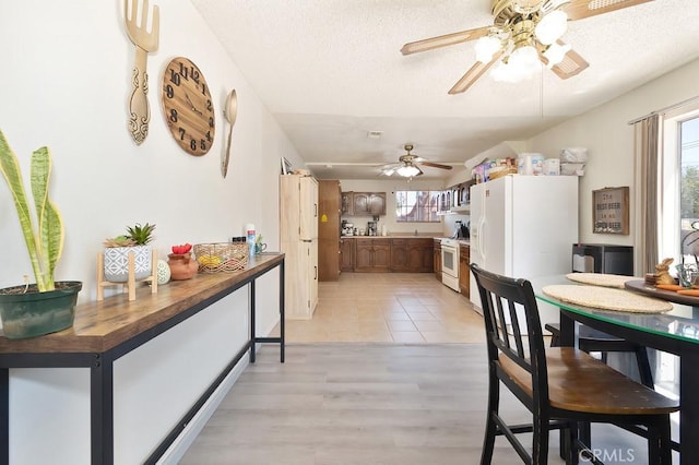 1107 B St, Brawley, CA 92227 - kitchen featuring brown cabinets, white appliances, a textured ceiling, light wood-style flooring, and a ceiling fan