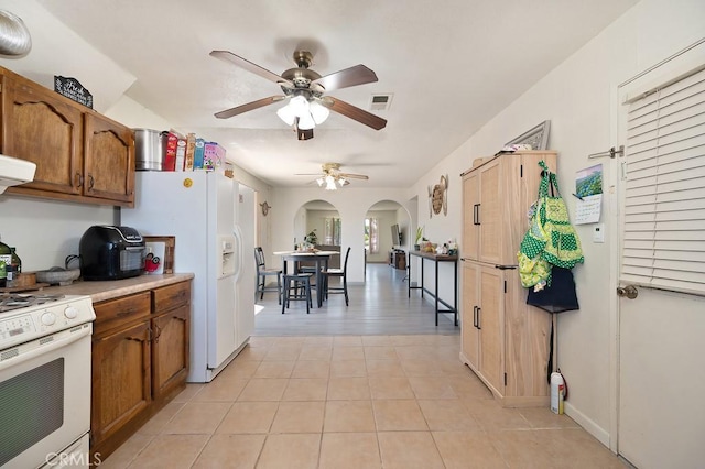 1107 B St, Brawley, CA 92227 - kitchen with brown cabinetry, a ceiling fan, visible vents, arched walkways, and white appliances