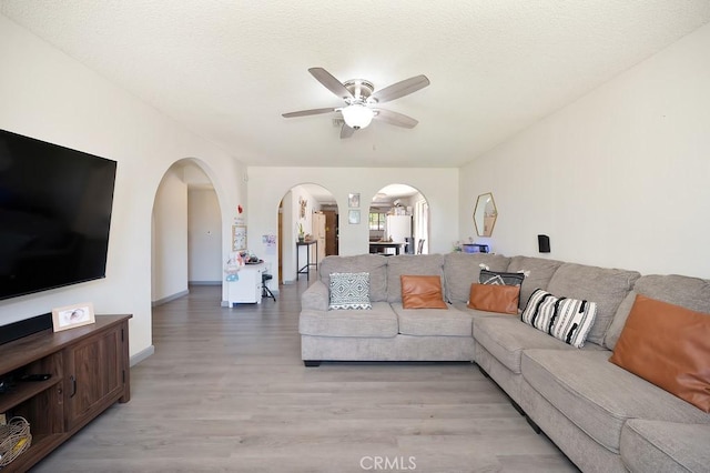 1107 B St, Brawley, CA 92227 - living area featuring baseboards, arched walkways, light wood finished floors, and ceiling fan