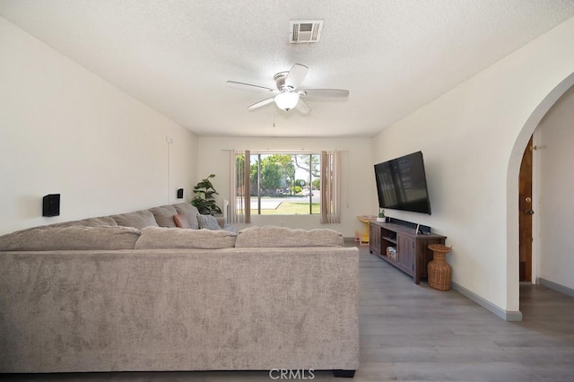 1107 B St, Brawley, CA 92227 - living room featuring visible vents, a ceiling fan, wood finished floors, baseboards, and arched walkways