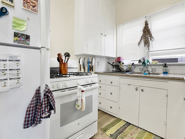 1407 Obispo Ave, Long Beach, CA 90804 - kitchen with white appliances, white cabinets, a sink, light wood-style flooring, and decorative backsplash