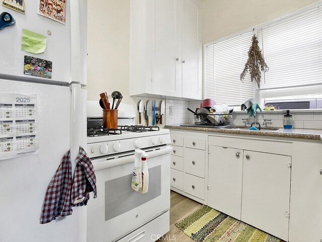 1407 Obispo Ave, Long Beach, CA 90804 - kitchen with white appliances, white cabinets, a sink, light wood-style flooring, and decorative backsplash
